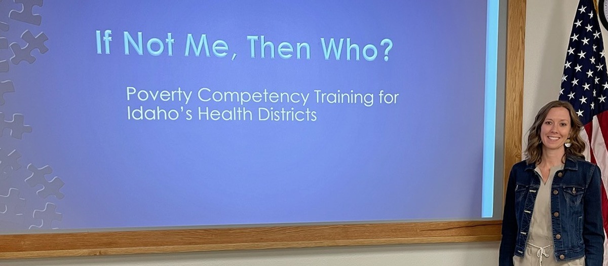 Woman stands in front of slide that reads "If not me, then who?"